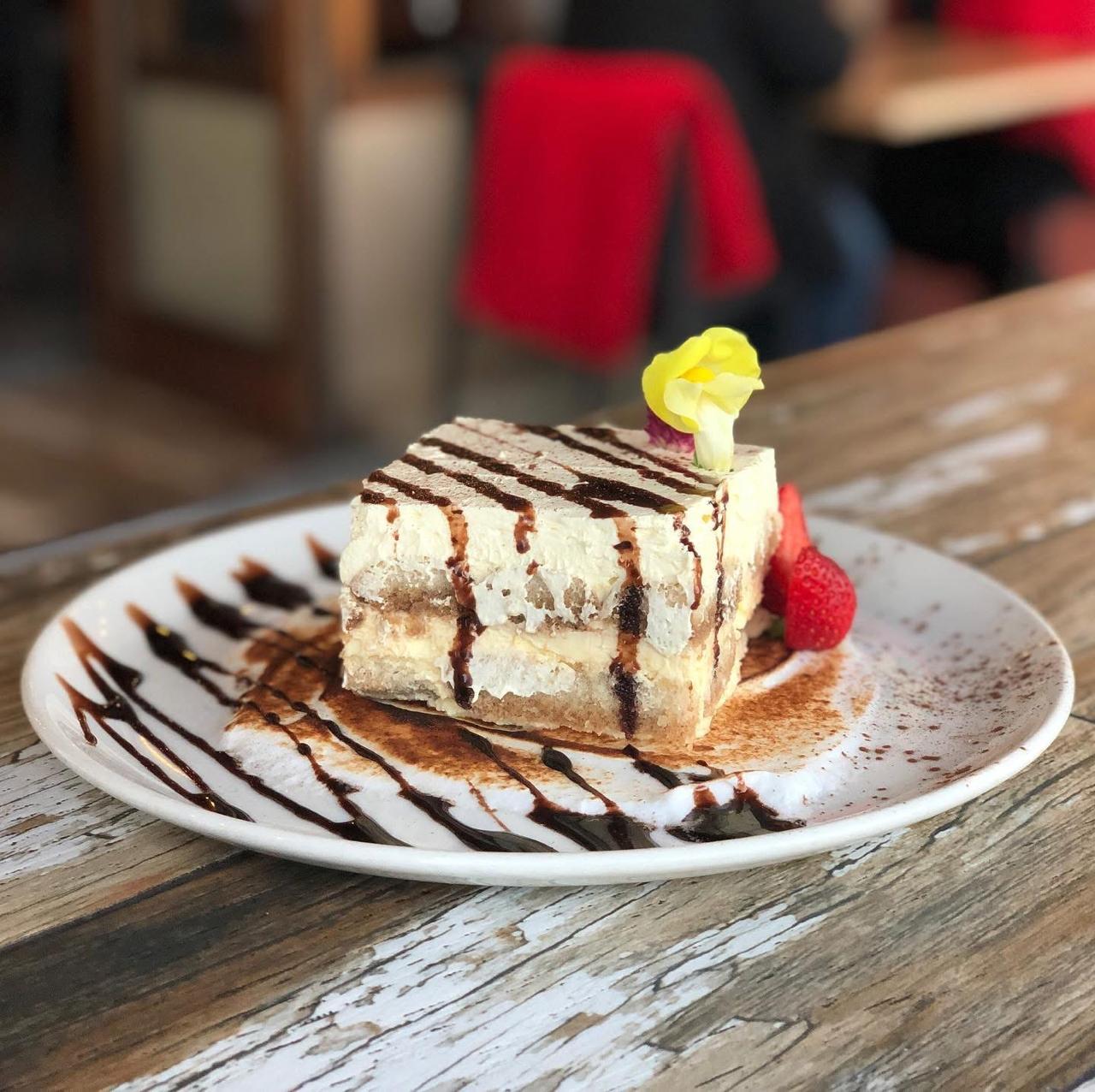 Layered tiramisu drizzled with chocolate sauce and fresh berries